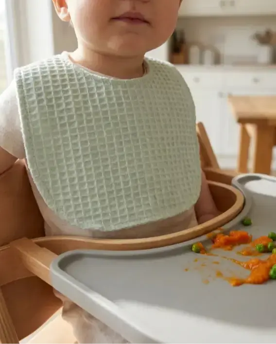 Su geçirmez mama önlüğü takan bebek, diş çıkarma döneminde kıyafetlerini kuru tutan pamuklu ve emici tasarım.