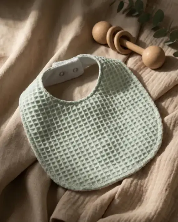 Pamuk dış yüzeyli, su geçirmez katmanlı mama önlüğü modeli, salya ve sıvı geçişini önleyen bebek önlüğü.